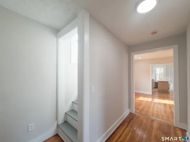 a view of hallway with bathroom and wooden floor