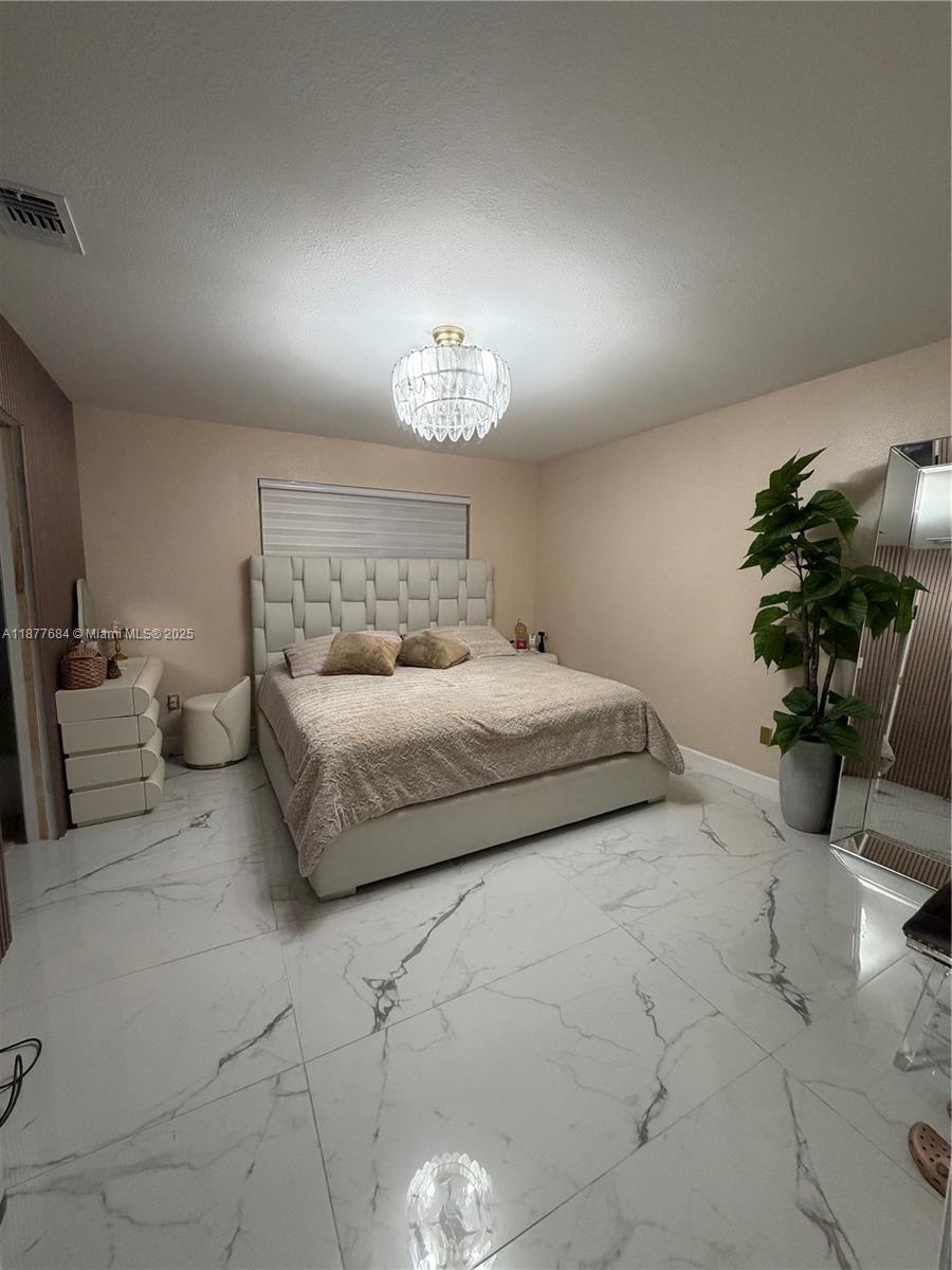 7684 Northwest 179th Street Hialeah, FL 33015 - Photo 4 of 13 a bedroom with a bed and a chandelier