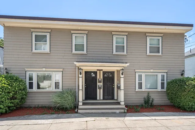 a view of a brick house with a large windows and plants