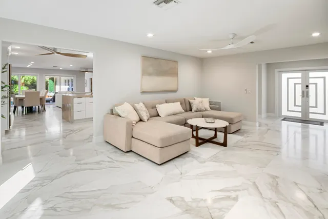 a dining hall with stainless steel appliances kitchen island granite countertop a dining table chairs and a refrigerator