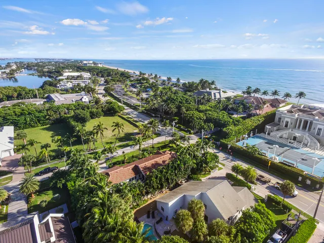a view of a house with a yard and palm trees