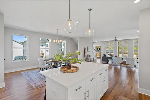 a view of a dining room and livingroom with furniture wooden floor a rug a potted plant and a chandelier