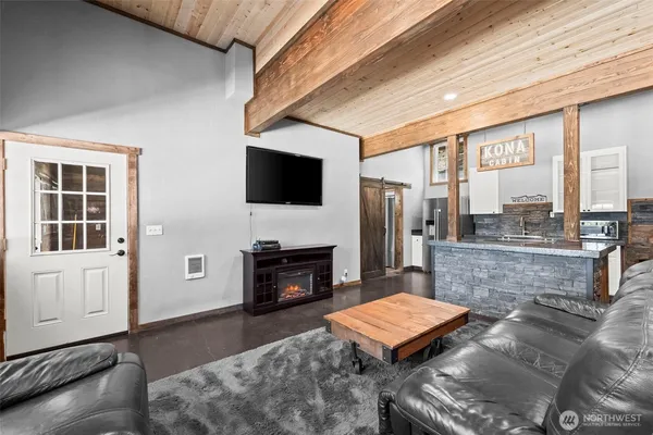 a living room with furniture a flat screen tv and kitchen view