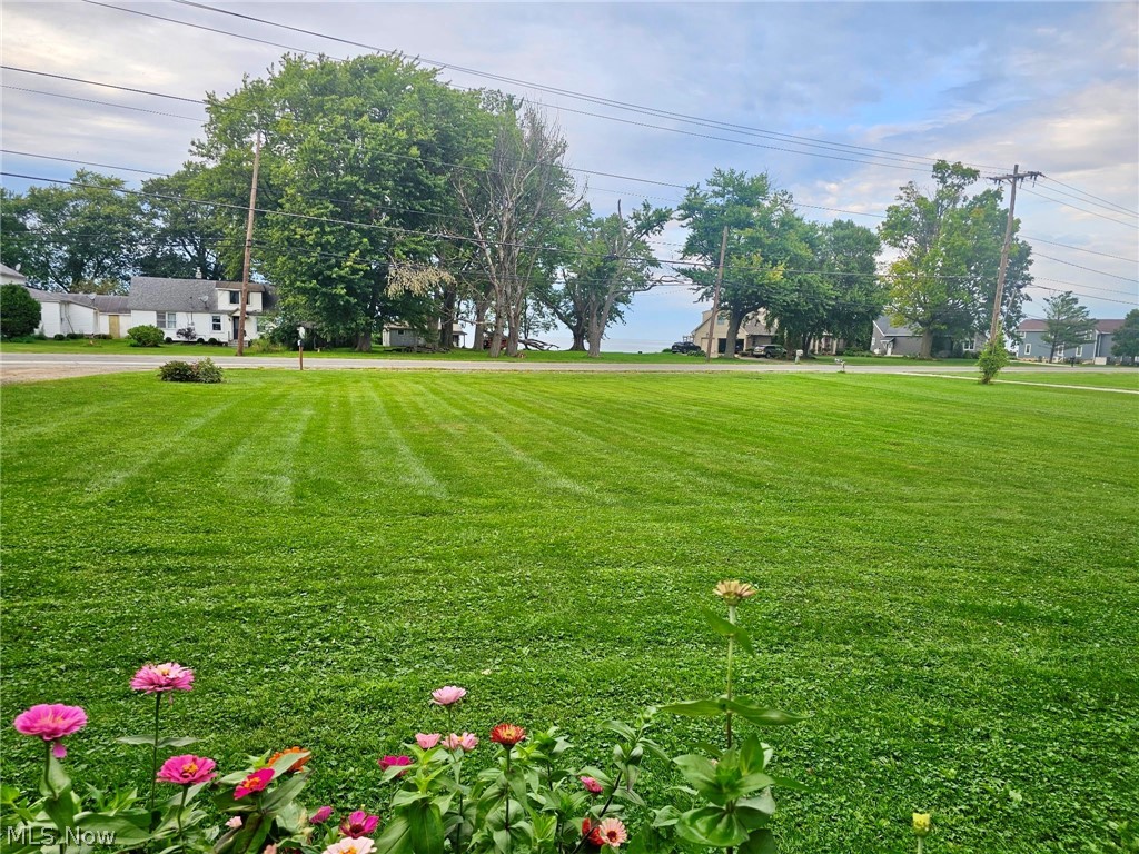 6620 West Lake Road Vermilion, OH 44089 - Photo 9 of 34 Expansive lawn with manicured landscaping, mature trees, and perennial flower beds