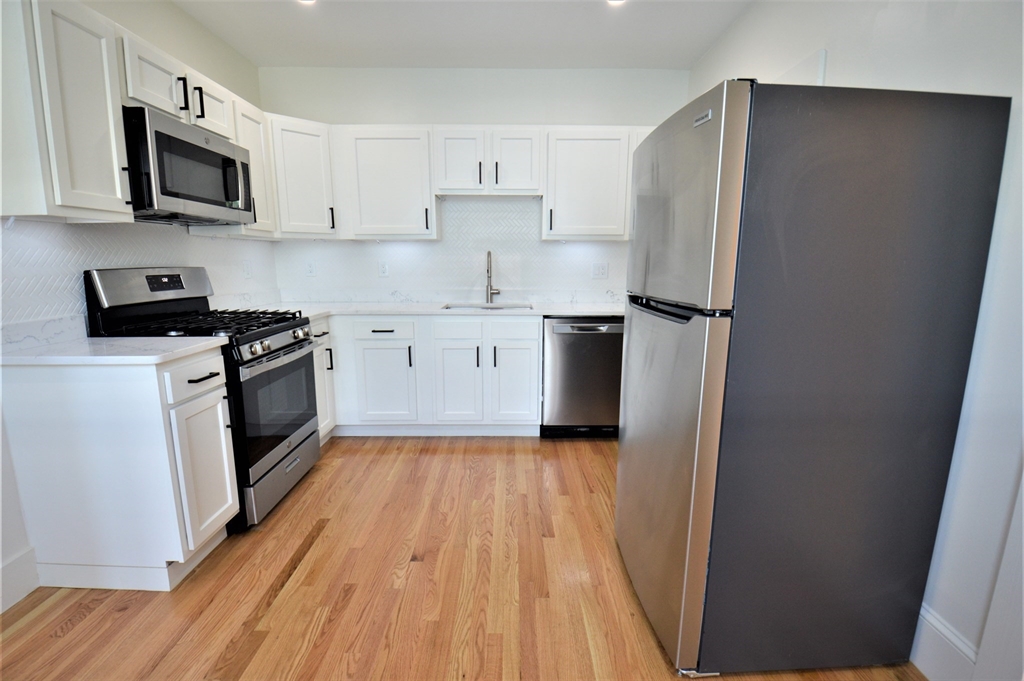 27 Ransom Road, Unit 2 Boston, MA 02135 - Photo 4 of 29 a kitchen with a sink a microwave a refrigerator and cabinets