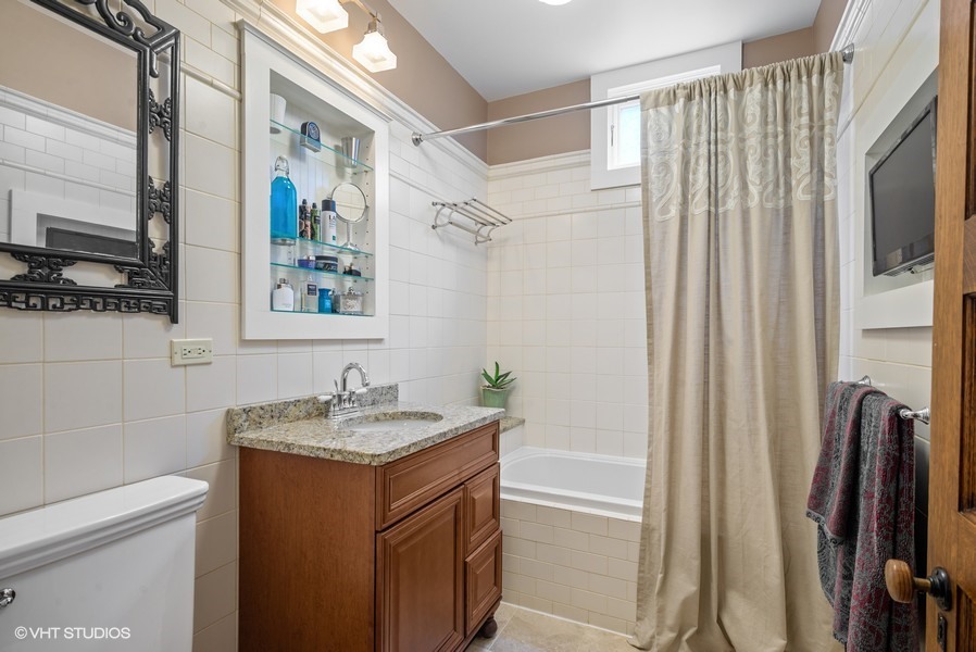 4050 North Kenmore Avenue Chicago, IL 60613 - Photo 19 of 32 a bathroom with a granite countertop sink a mirror and a shower