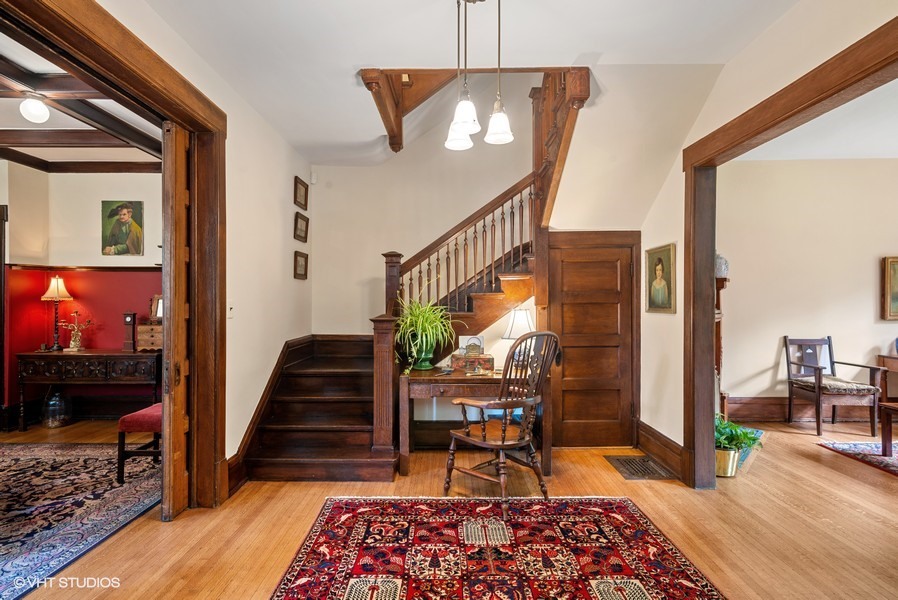 4050 North Kenmore Avenue Chicago, IL 60613 - Photo 3 of 32 a bedroom with wooden floor stairs and a chandelier