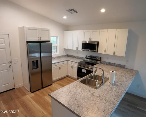 a kitchen with stainless steel appliances granite countertop a sink stove and refrigerator