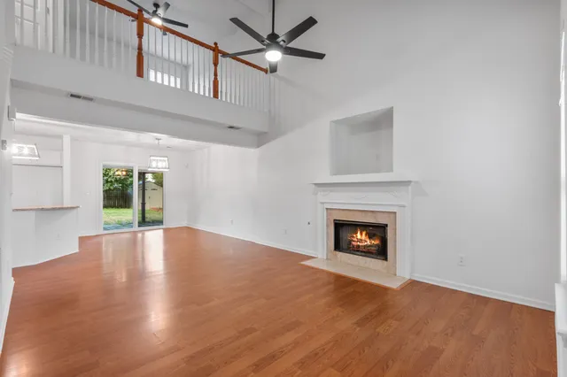 a view of an empty room with wooden floor fireplace and a window