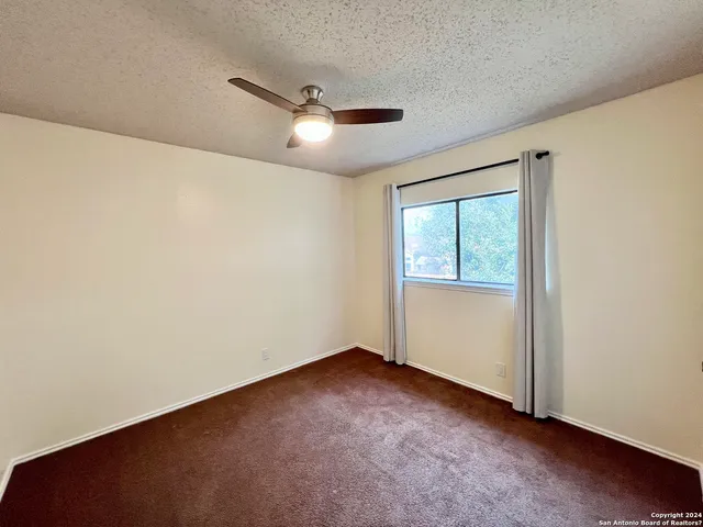 an empty room with a window and a fan