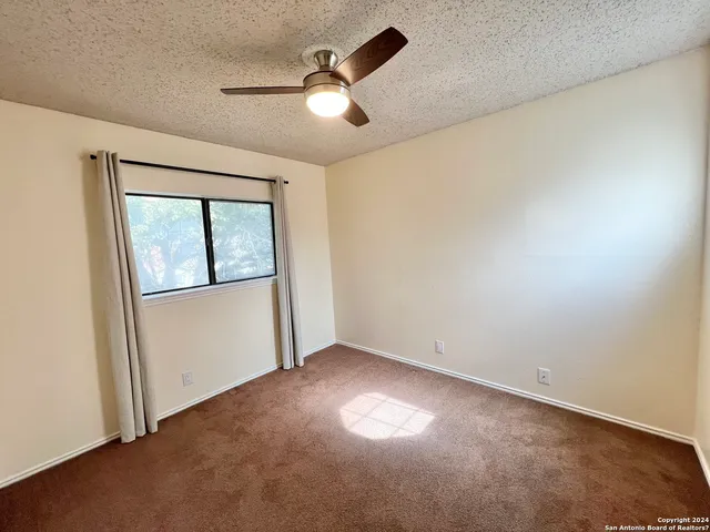 an empty room with a window and ceiling fan