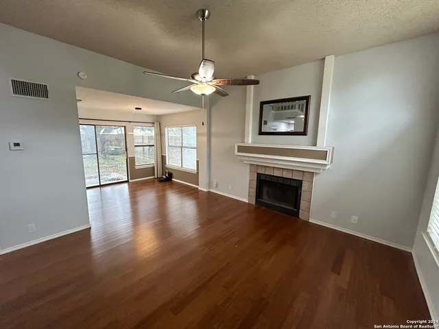 an empty room with wooden floor fireplace and windows