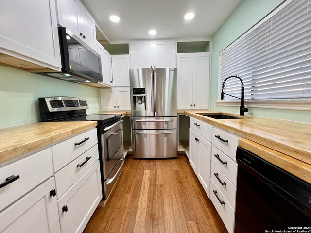 a kitchen with stainless steel appliances granite countertop a sink a stove and refrigerator
