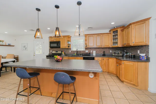 a kitchen with stainless steel appliances granite countertop a sink a stove and a wooden floors