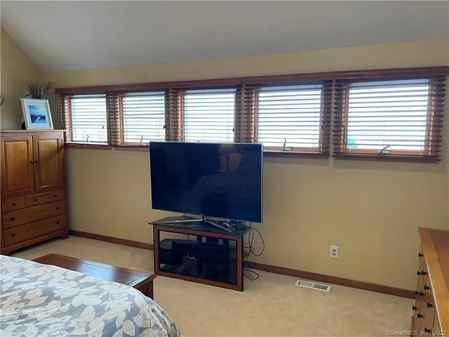 a bedroom with windows and flat screen tv