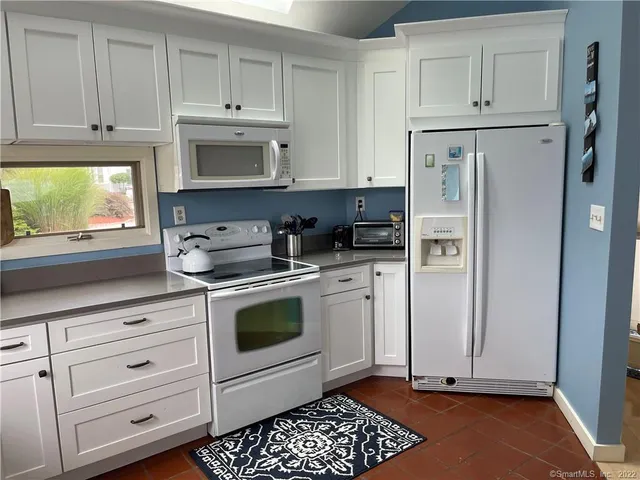 a kitchen with granite countertop white cabinets and white appliances