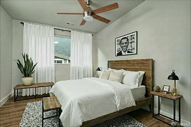 a bedroom with a bed a window and potted plant on the dresser