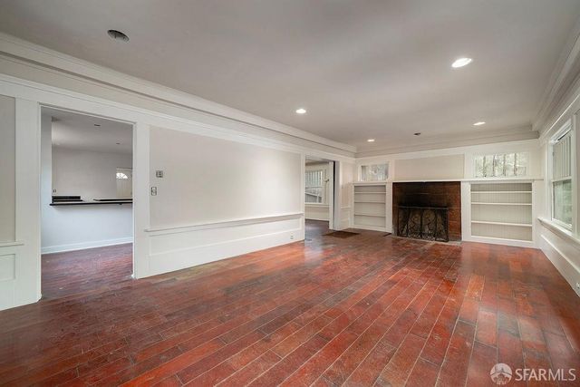 a view of empty room with wooden floor and fireplace