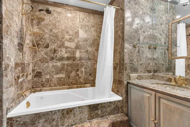 a bathroom with a granite countertop bathtub shower sink and vanity