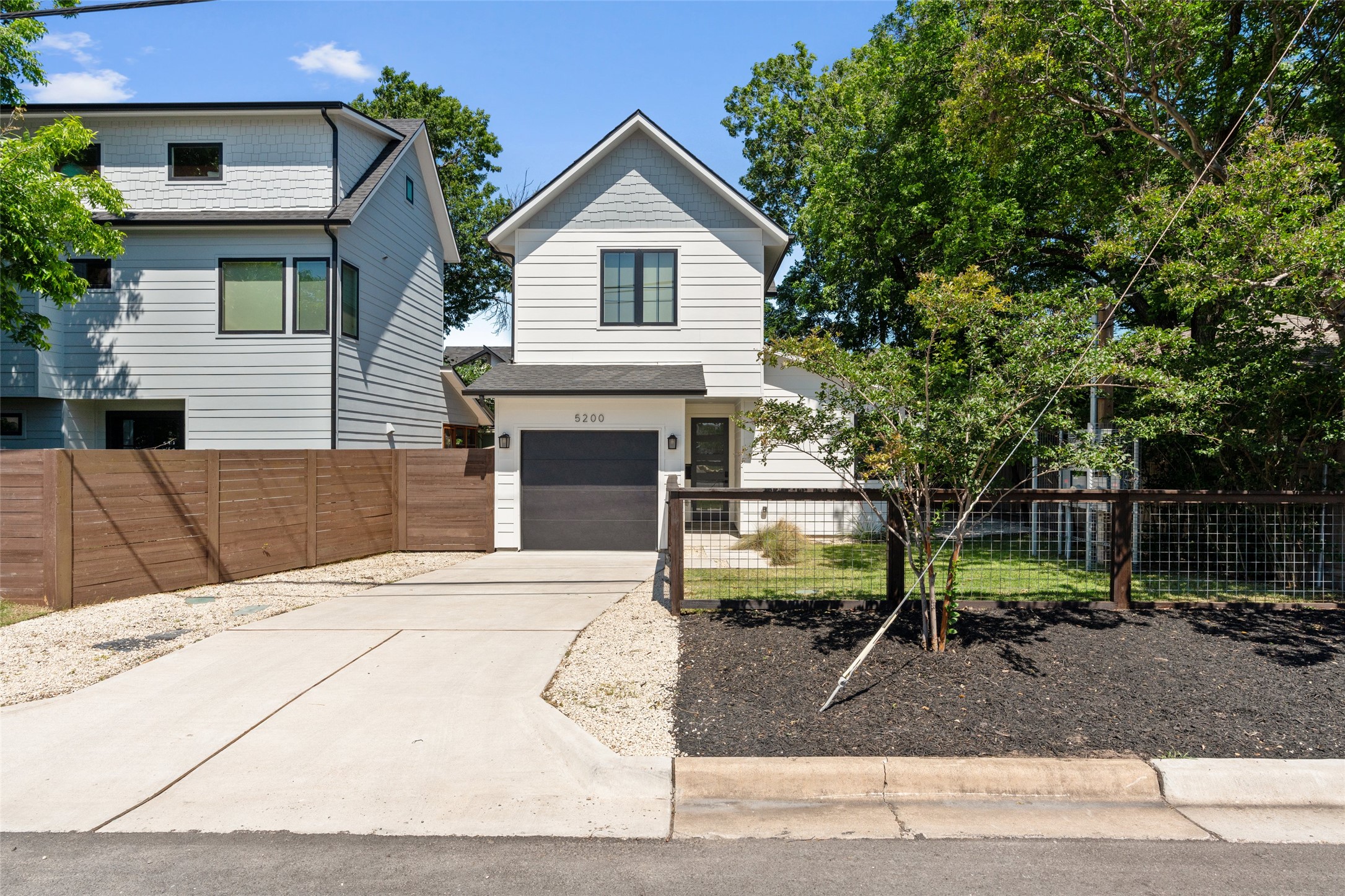 5200 Grover Avenue Austin, TX 78756 - Photo 1 of 32 Modern two-story residence featuring white siding, a single-car garage, and dark-framed windows. Fully fenced front yard.