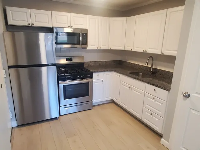 a kitchen with white cabinets and stainless steel appliances
