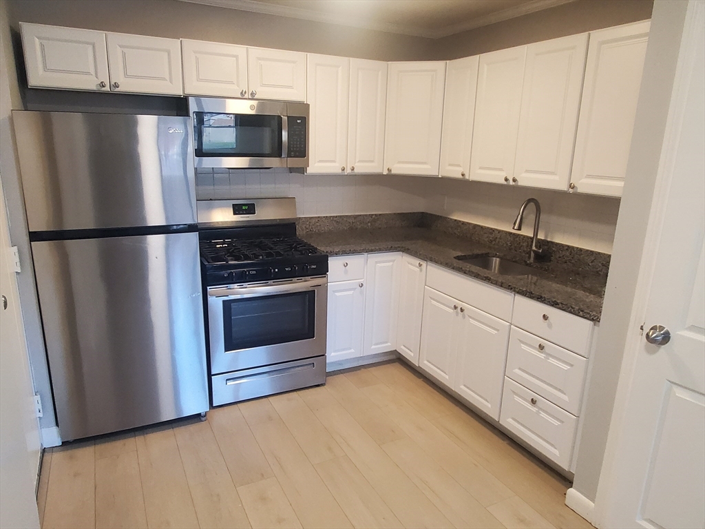 a kitchen with white cabinets and stainless steel appliances