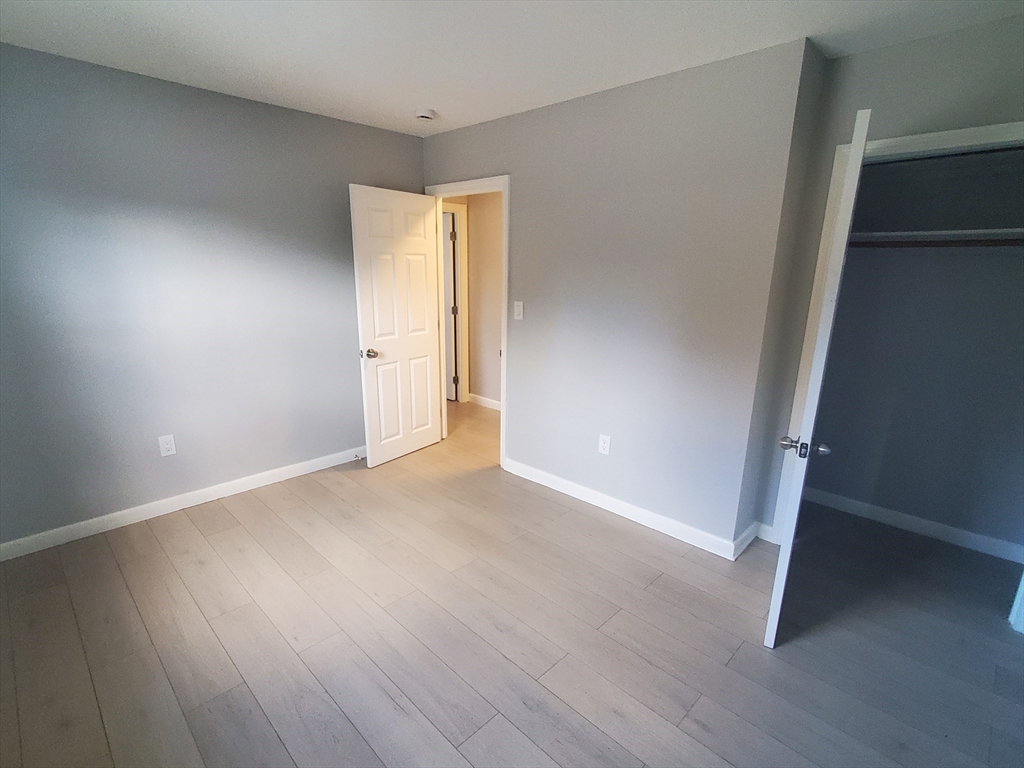 215 Pearl Street, Unit 8 Stoughton, MA 02072 - Photo 9 of 18 a view of an empty room with wooden floor and a window