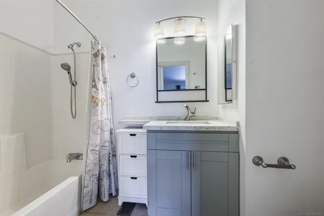 a bathroom with a bath tub sink mirror and shower