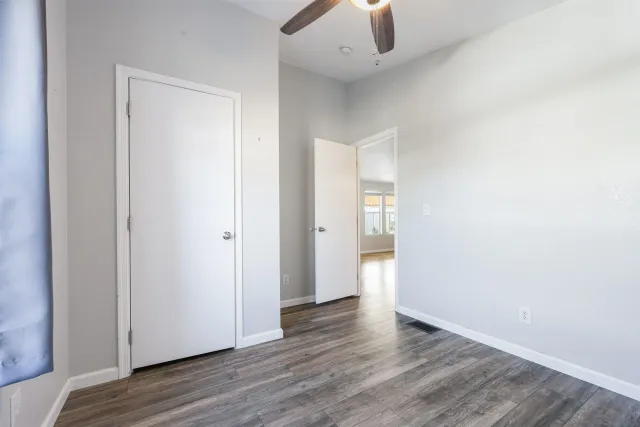 an empty room with wooden floor and ceiling fan