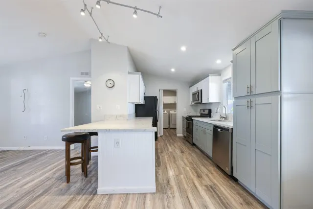 a large kitchen with a center island wooden floor stainless steel appliances and cabinets