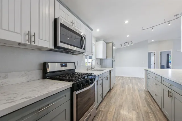 a kitchen with stainless steel appliances granite countertop a stove a sink and a microwave