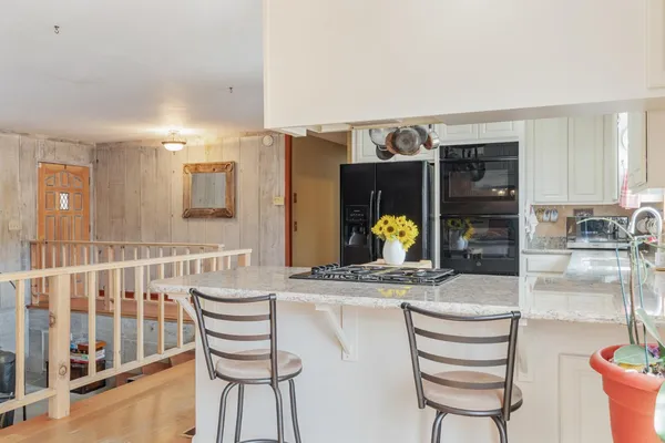 a dining hall with stainless steel appliances kitchen island granite countertop a table and chairs