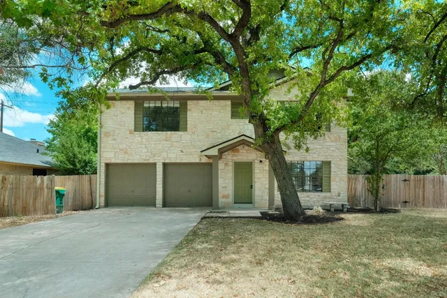 front view of a house with a yard and an trees