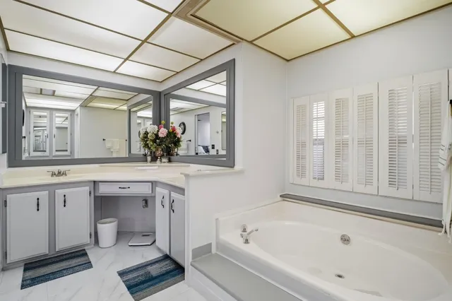 a spacious bathroom with a tub sink and mirror