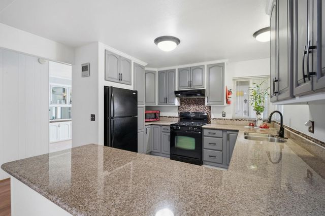 a kitchen with granite countertop a refrigerator stove top oven and sink