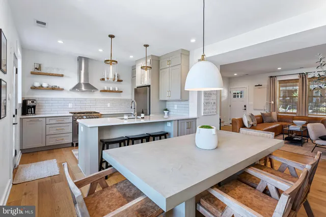 a kitchen with stainless steel appliances a dining table wooden floor and a refrigerator