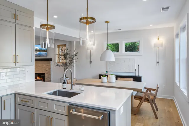 a kitchen with stainless steel appliances a refrigerator a sink a stove and white cabinets