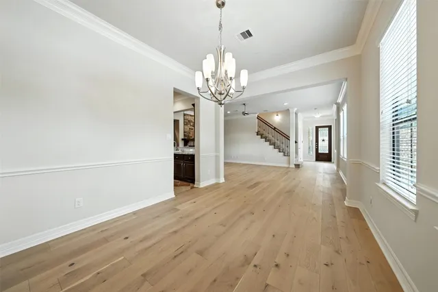 a view of a hallway with wooden floor and a chandelier