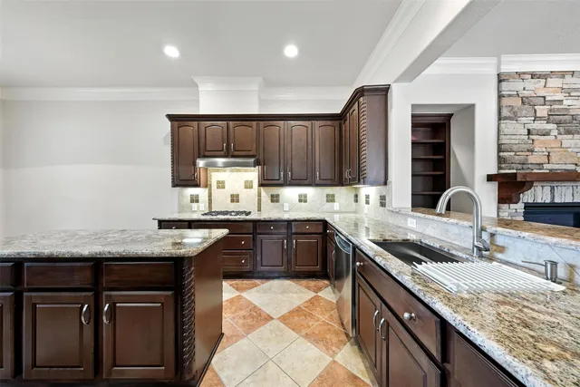 a kitchen with granite countertop kitchen island stainless steel appliances a sink stove and cabinets