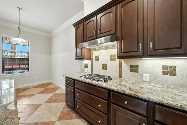 a kitchen with granite countertop a sink a stove and cabinets