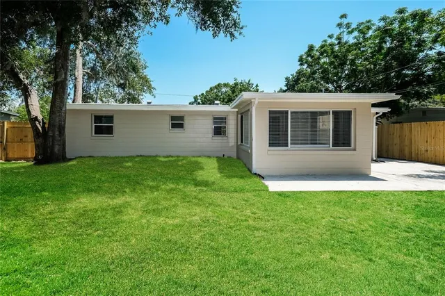 a backyard of a house with potted plants and large tree
