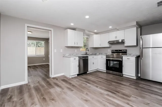 a kitchen with a white cabinets a sink and stainless steel appliances
