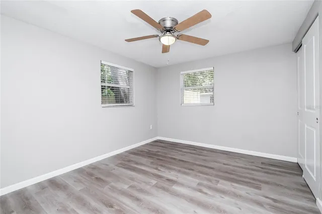 an empty room with wooden floor and ceiling fan