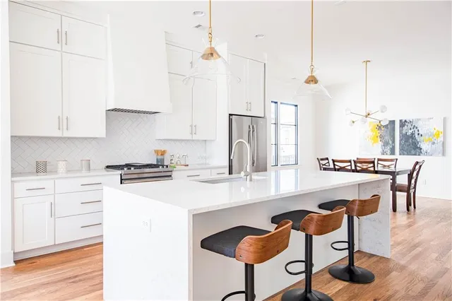 a kitchen with stainless steel appliances kitchen island a table chairs in it and white cabinets