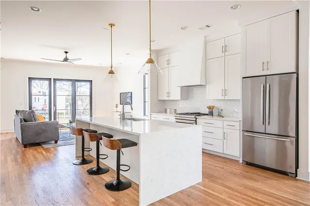 a kitchen with stainless steel appliances granite countertop a refrigerator a stove a sink dishwasher and a dining table with wooden floor