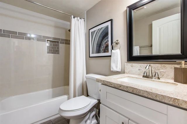 a bathroom with a granite countertop sink toilet and shower