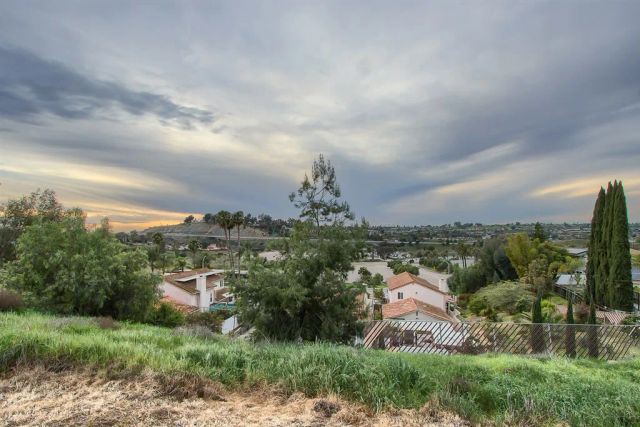 an aerial view of a city with lots of residential buildings green landscape and mountain view