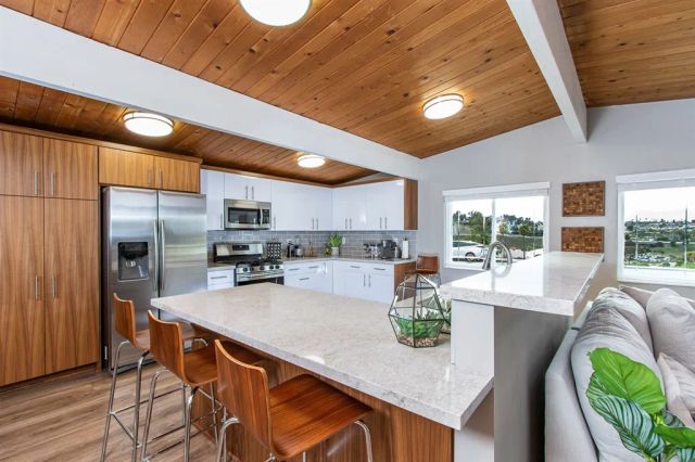 a kitchen with stainless steel appliances granite countertop a refrigerator a stove top oven a sink with island and chairs