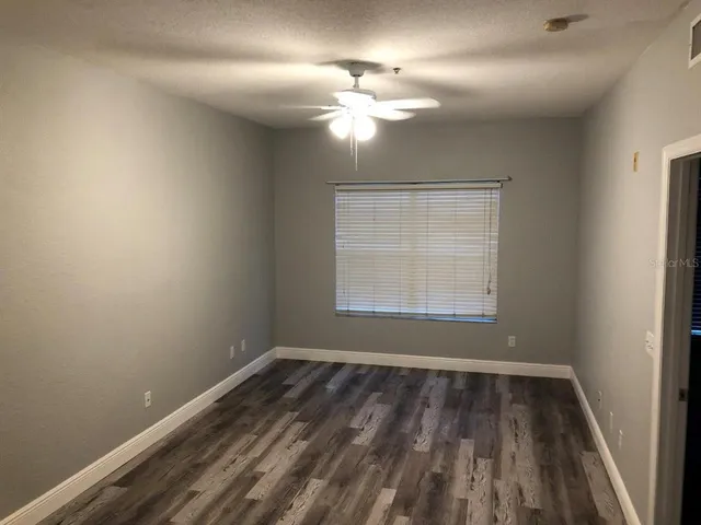 an empty room with wooden floor fan and window