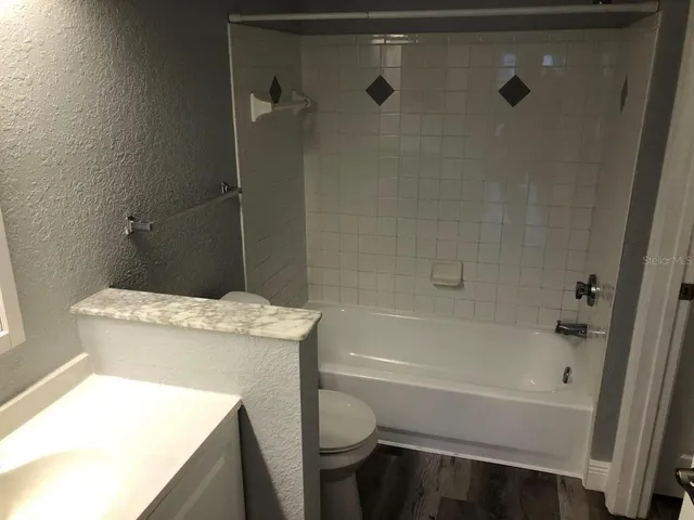 a bathroom with a granite countertop sink toilet and bathtub